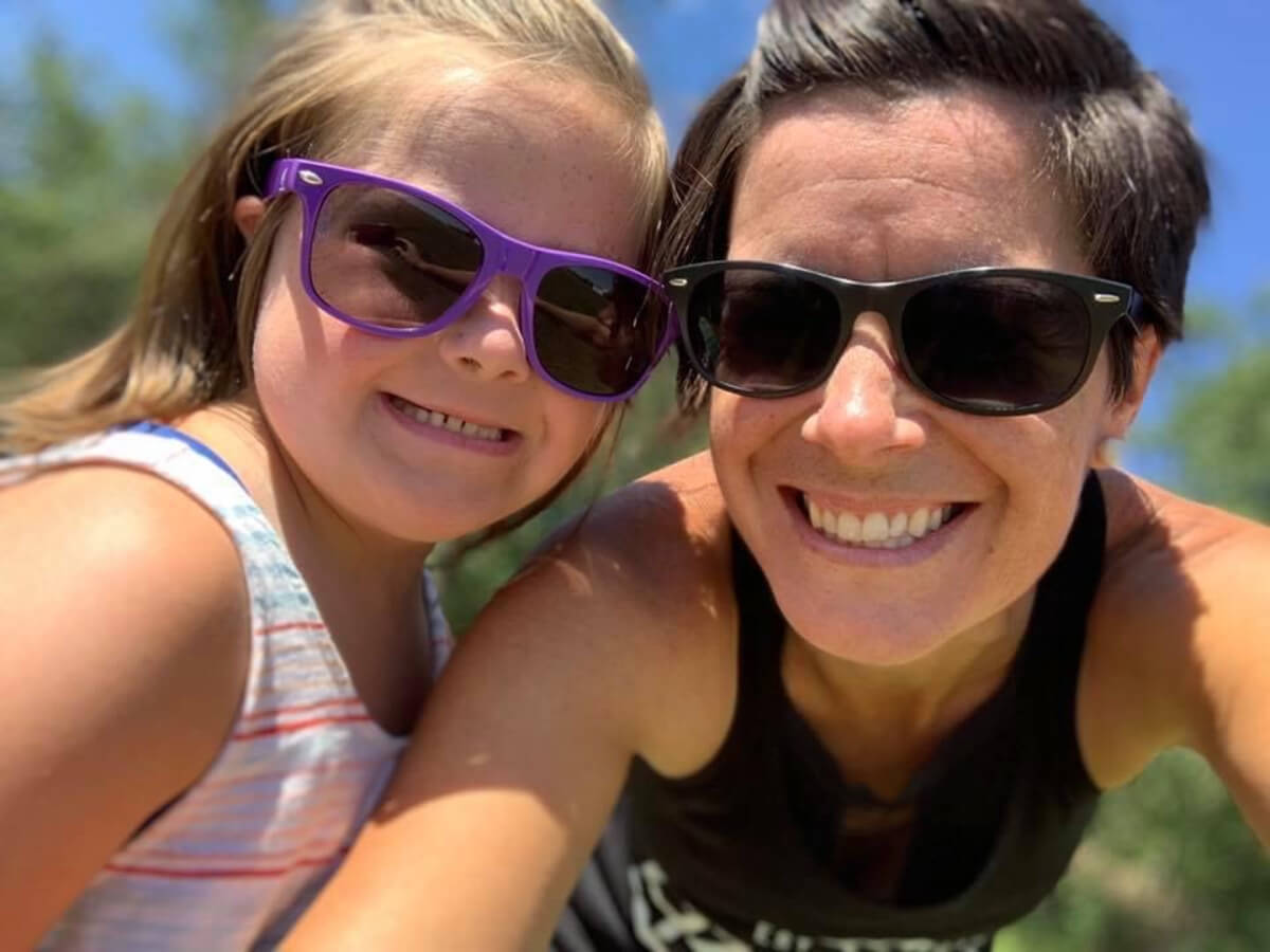 Woman and young girl wearing sunglasses and smiling at camera