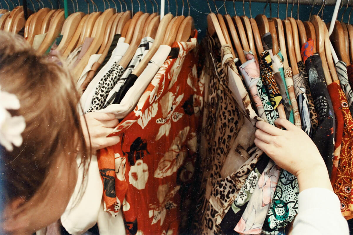 a woman checking recycled clothing on hangers