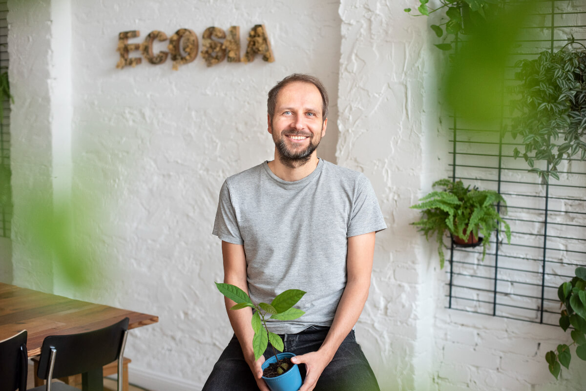 CEO of Ecosia, Christian Kroll, sitting and surrounded by plants in a white room