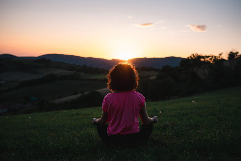 woman meditating outside at sunset for mental wellness