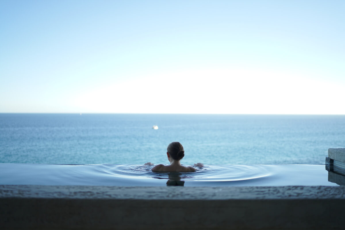 woman immersed in a pool overlooking the ocean, one of many natural anxiety remedies