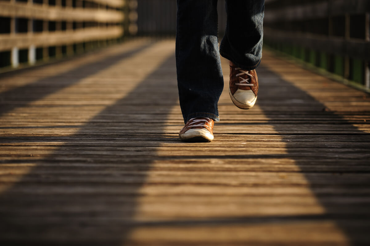 feet and lower legs of a person walking on a bridge 