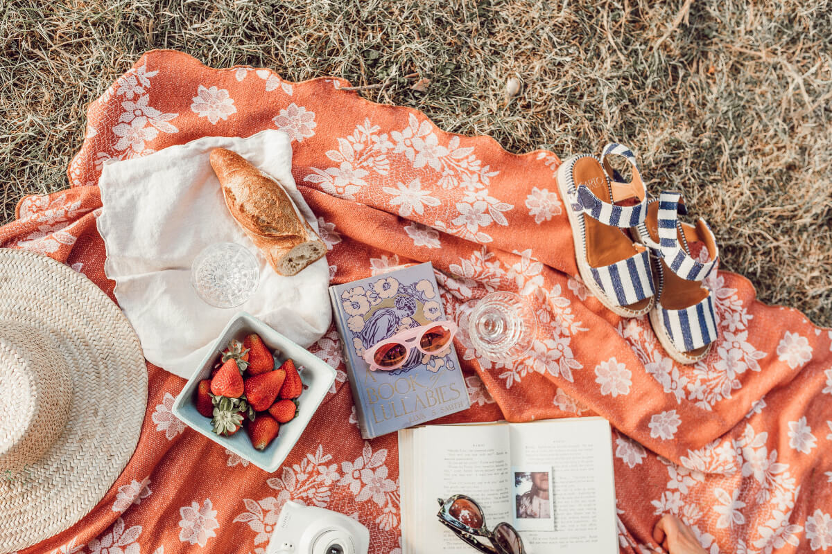 orange blanket with fruit, glasses, sandals and summer 2021 books