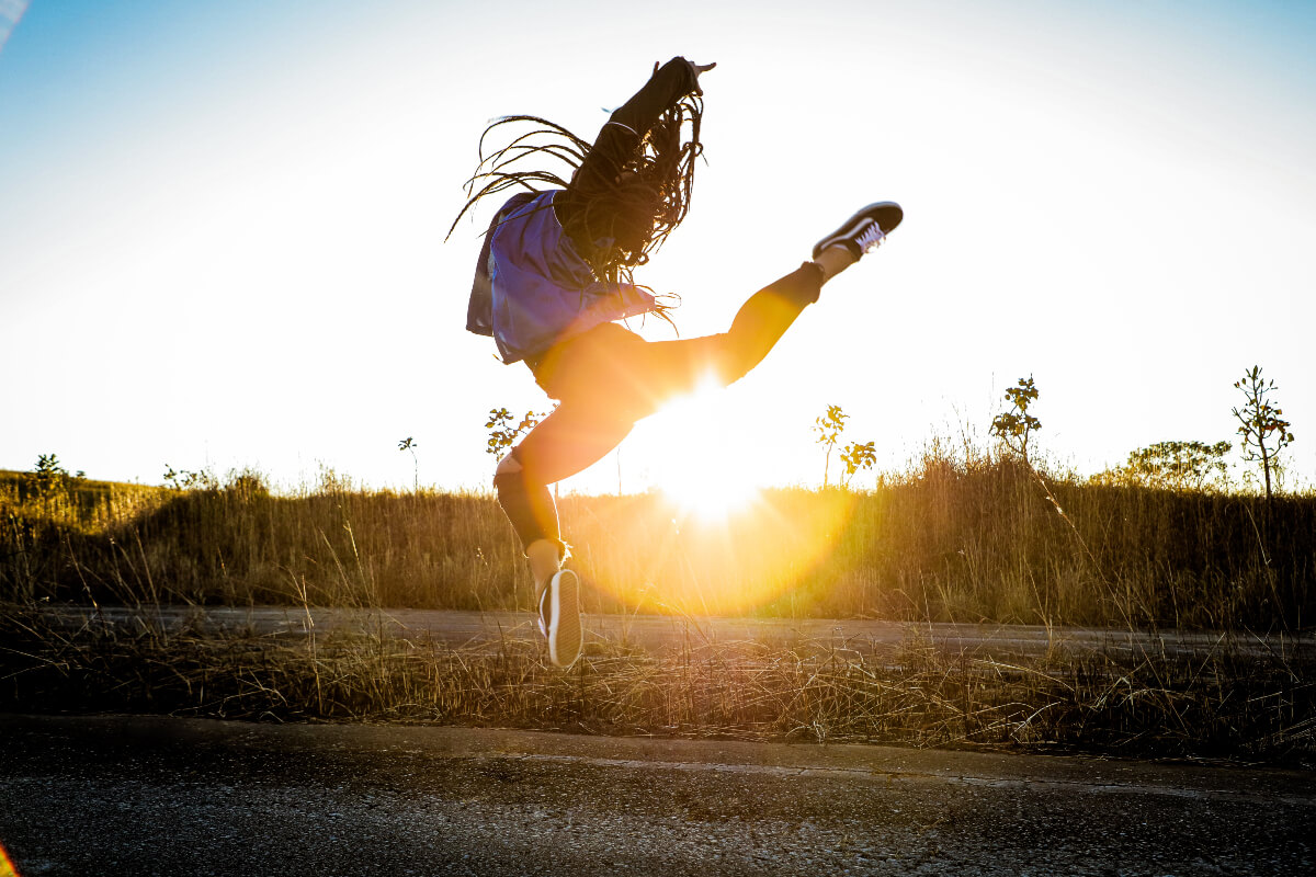 young woman jumping above the ground at sunset, feeling great as a weekday vegan