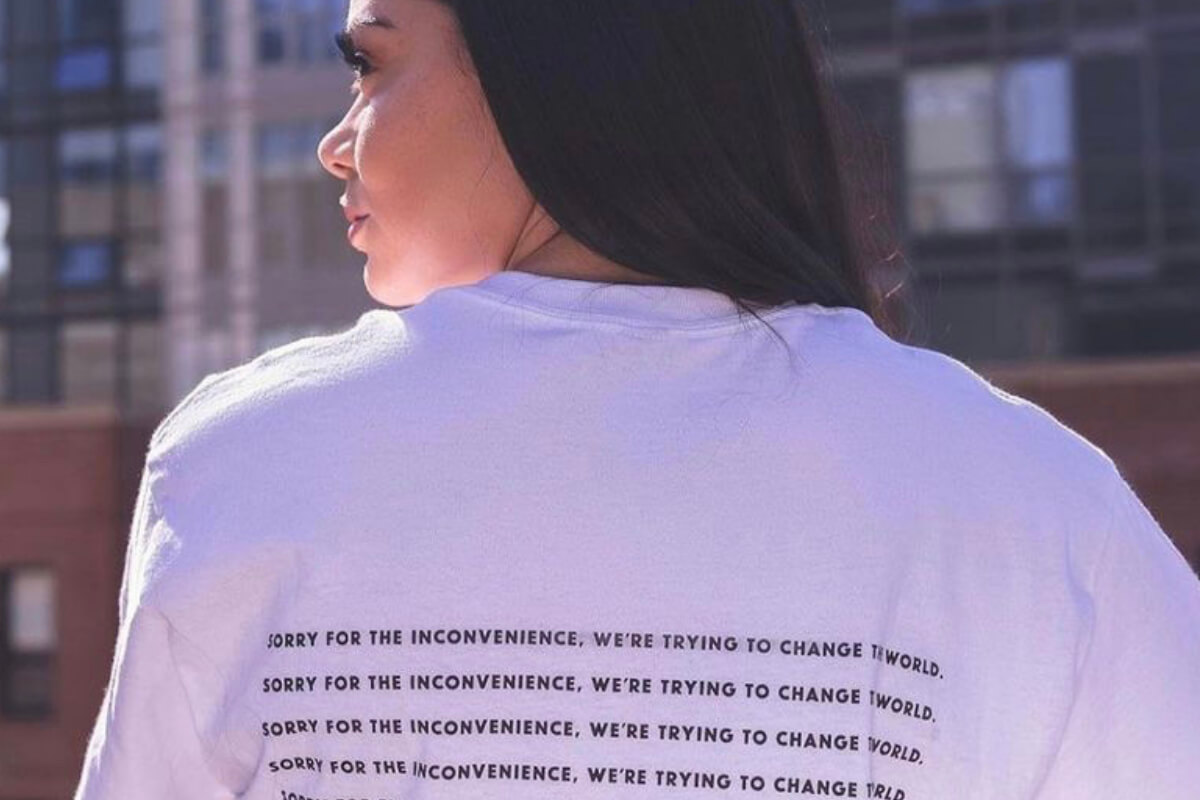 woman wearing a white t-shirt with protest writing on the back, supported by apathy is boring