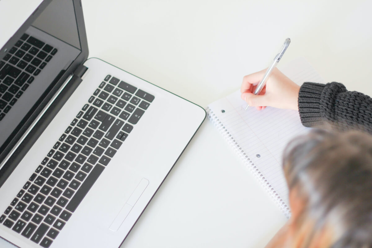 person working at laptop and writing as part of digital detox