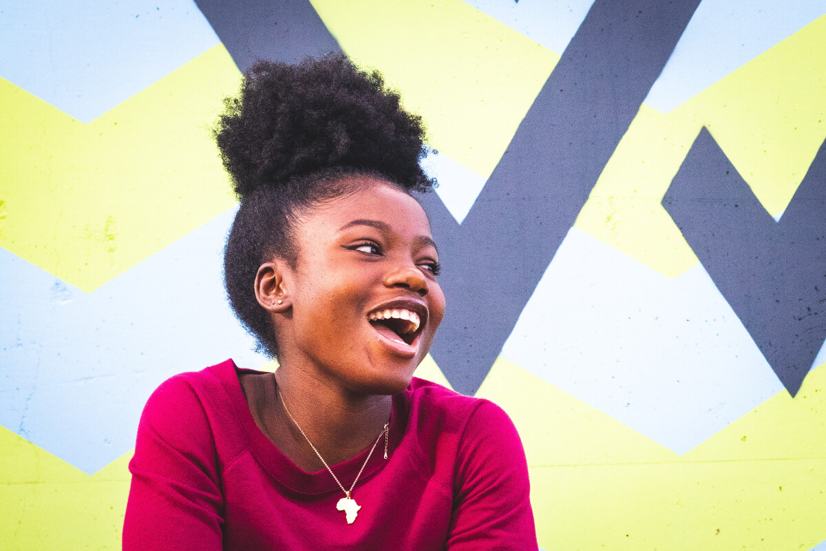 a young black woman smiling happily and looking away