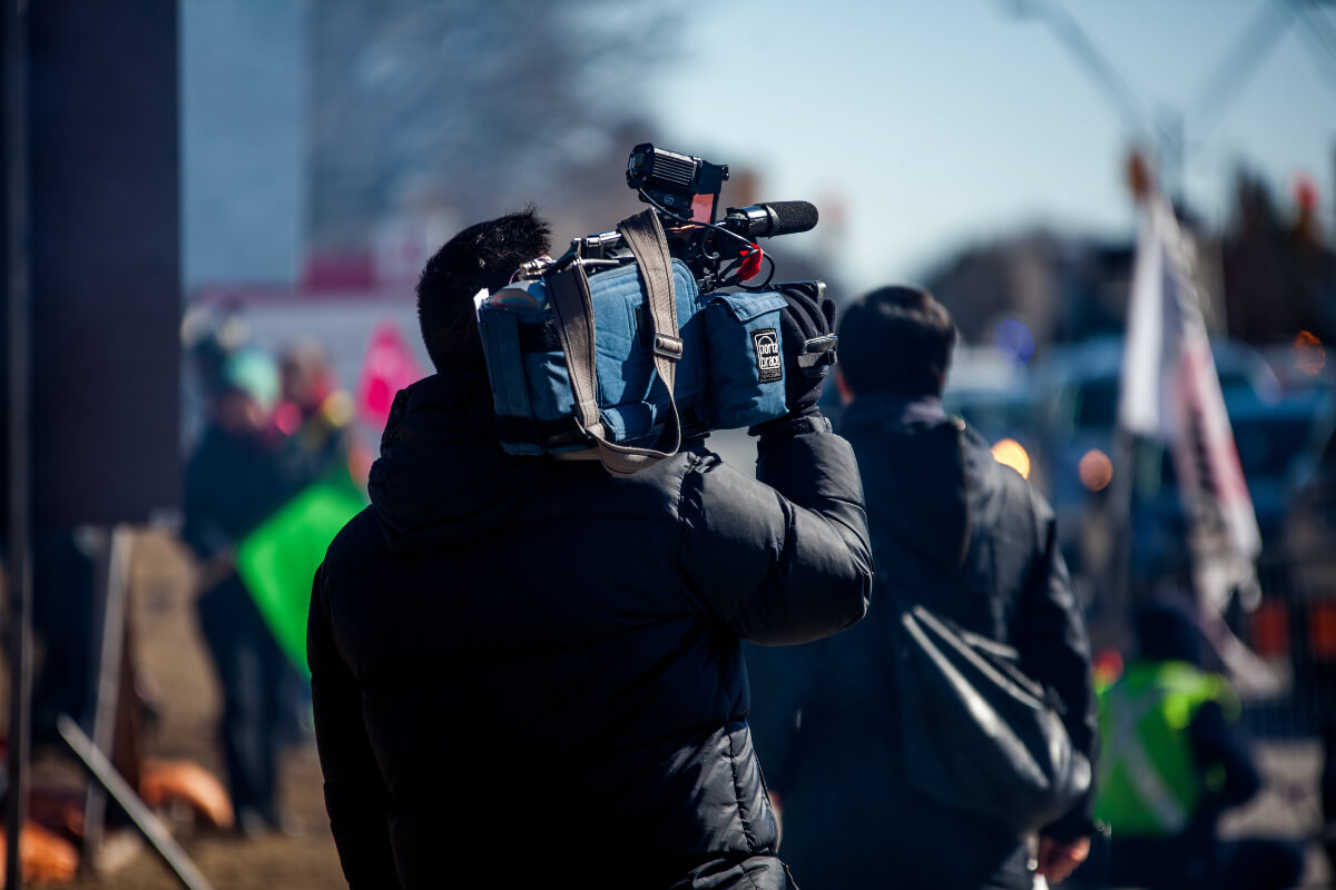 man holding a movie camera to document Indigenous Peoples’ Day 2021