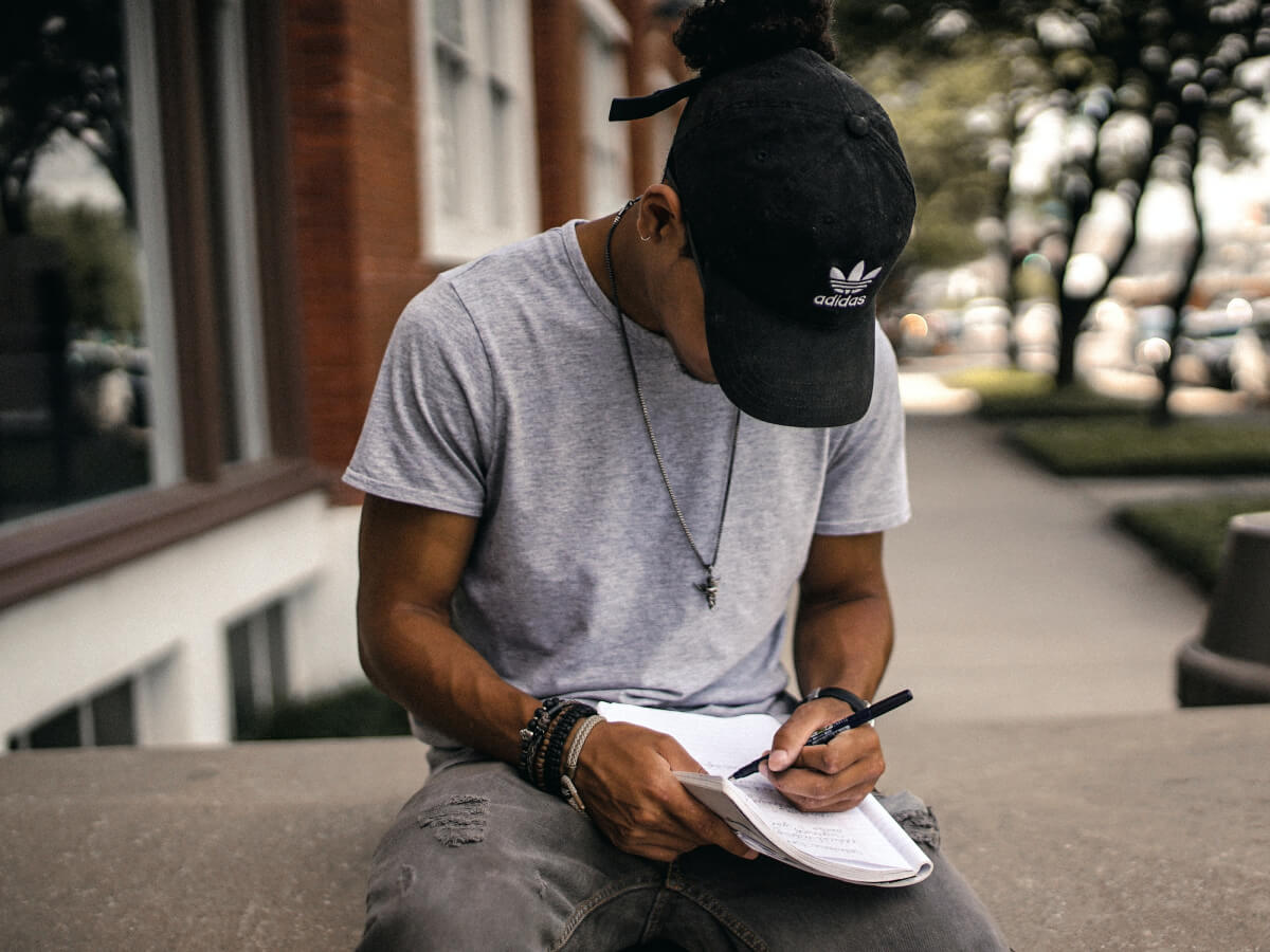 a man sitting outside and writing in a book 