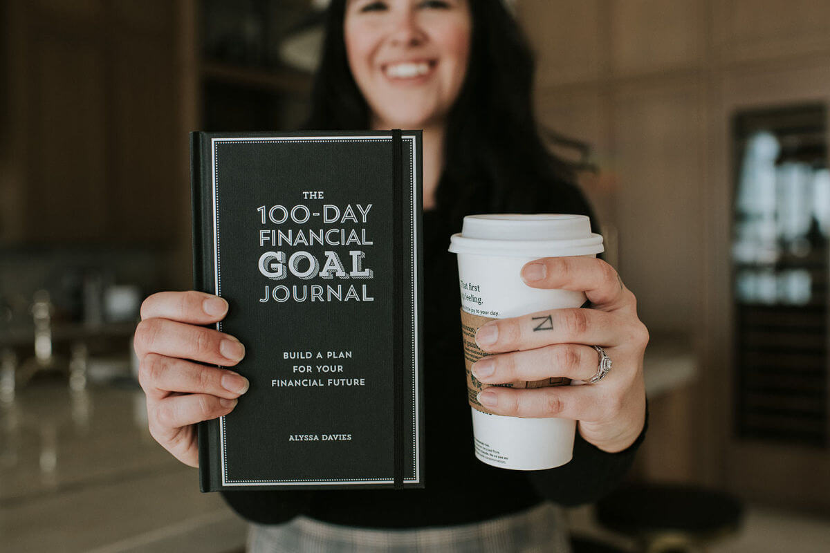 woman holding up financial goal journal to help with investing