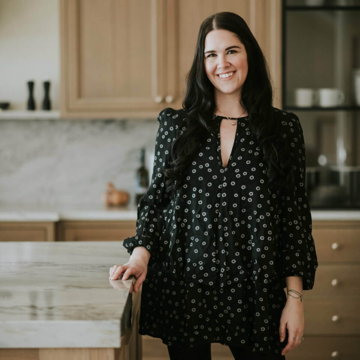 woman standing and smiling in black flowered dress