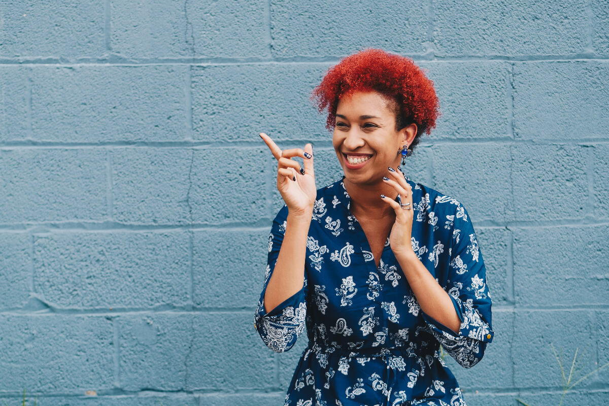 Person smiles excitedly wearing a navy, floral dress. Daylio Journal is an app for overall health, wellness, and self-care. 