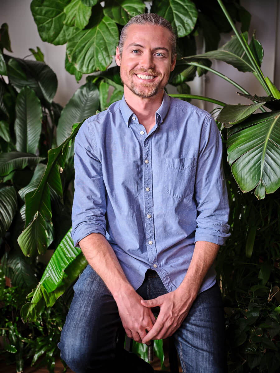 Morgan Wyatt smiles while surrounded by greenery. He is a scientist, inventor and co-founder of Greenlid.