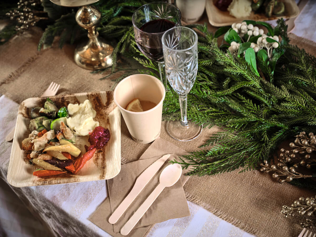 Table setting featuring Greenlid compostable products, including dinnerware, drinkware, and cutlery.