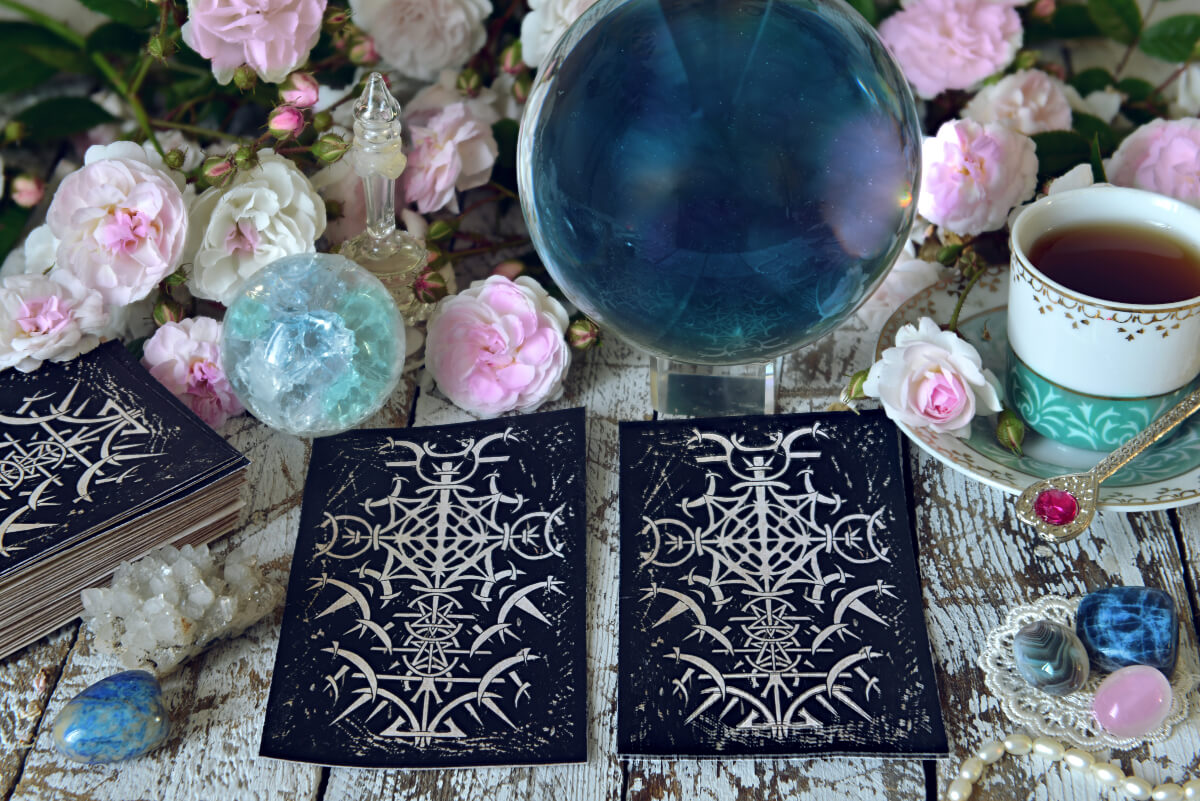 Black tarot cards surrounded by flowers and precious stones. 