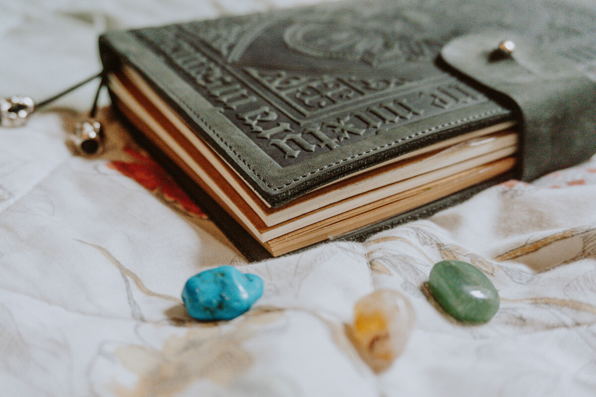 Urban witch leather-bound spell book and precious stones. 