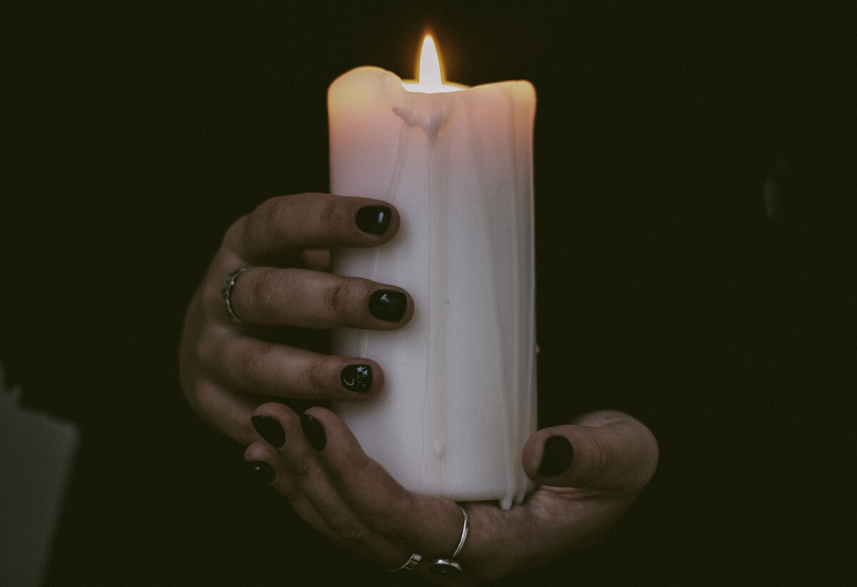Hands holding a white candle. 