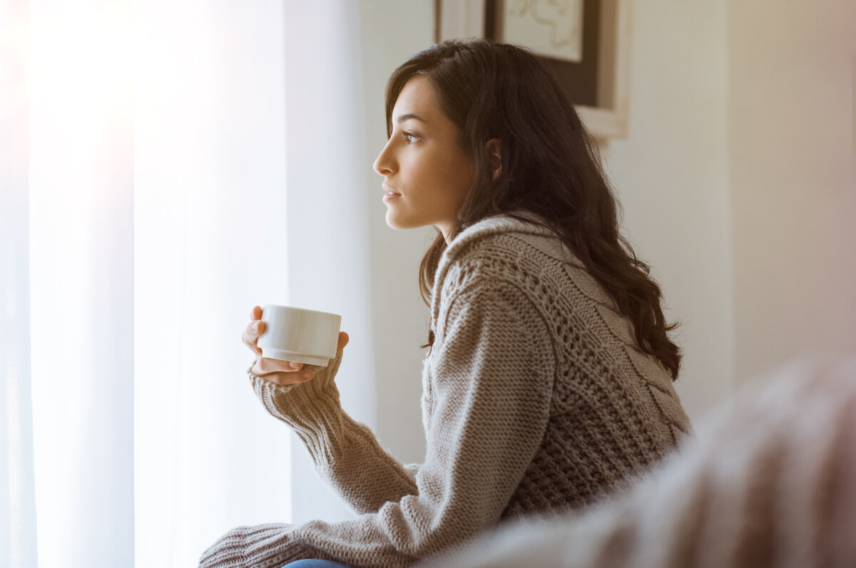 Woman in a cozy, white sweater holding a cup of tea
