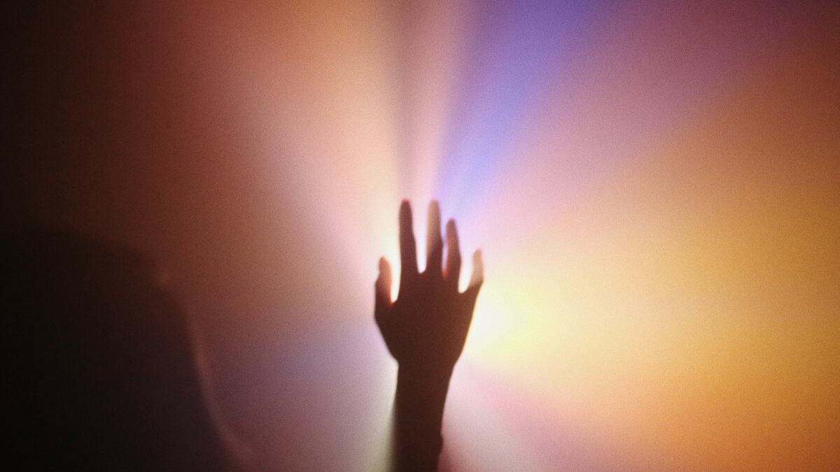 A silhouette of a hand surrounded by warm-colored light - an example of aura photography 