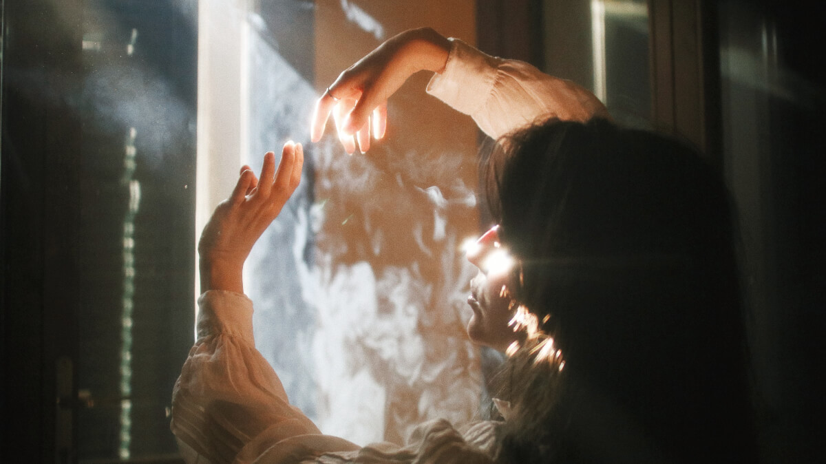 Image of a person looking out a window into the sunlight 