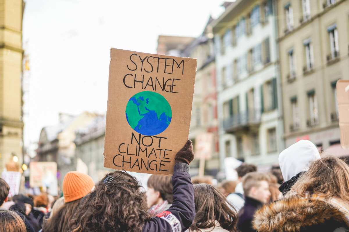 COP26 demonstrator holds a sign saying "System change, not climate change." 