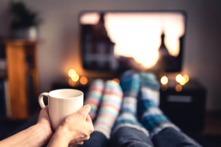 Cozy feet in socks snuggled in front of the TV watching Netflix Christmas movies