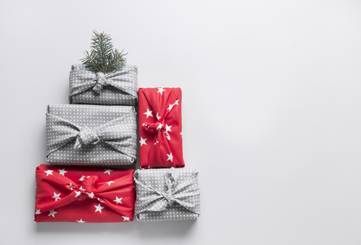 Christmas gifts wrapped in holiday-patterned fabrics. 