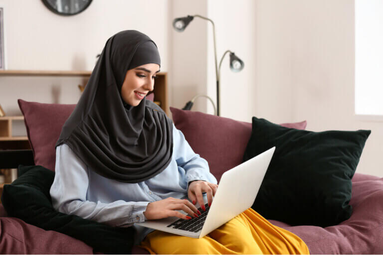 Woman sits in a cozy chair on her laptop using Yalla! Let's talk (YLT).