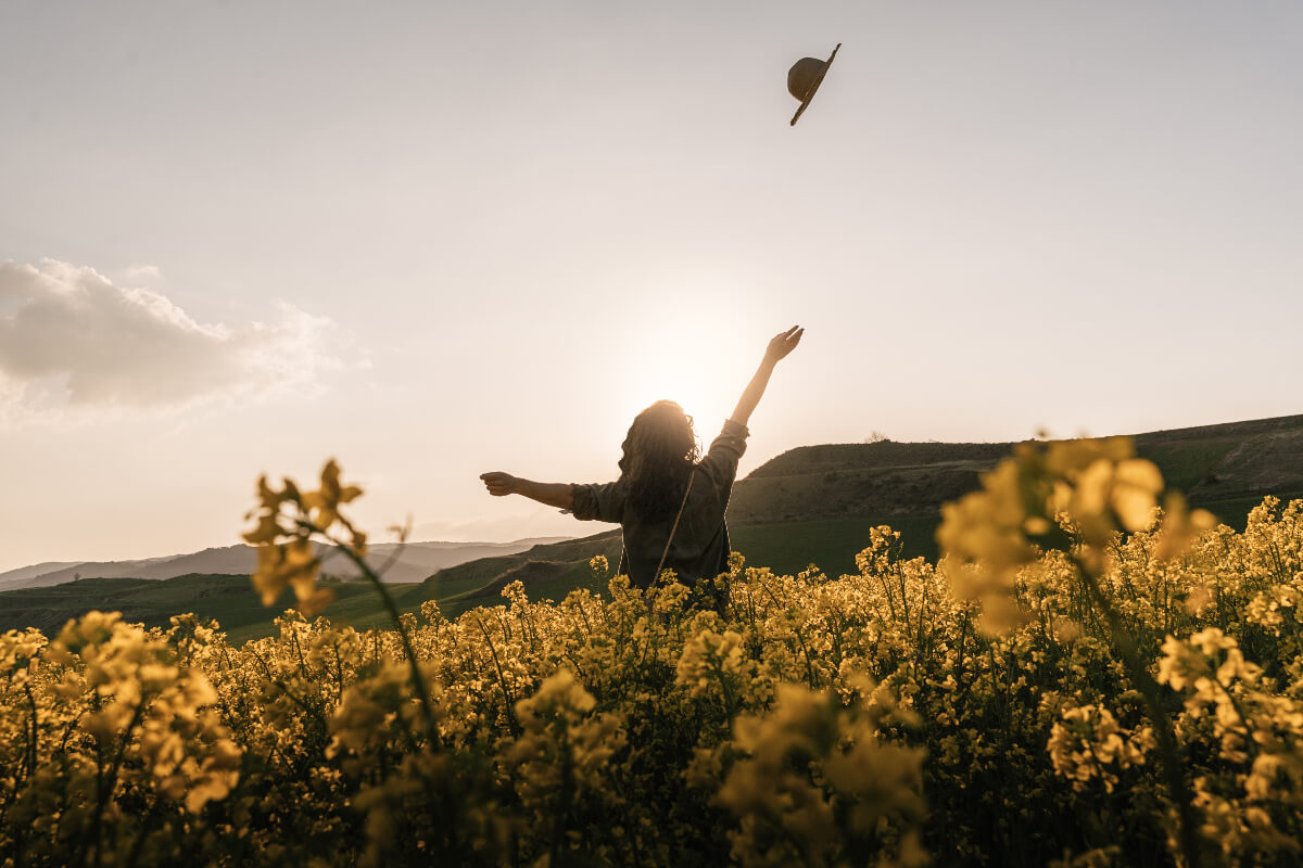 Person frolicking through a field of yellow flowers. 
