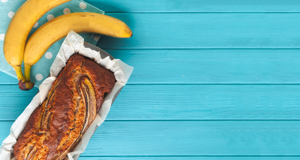 Bananas and banana bread sitting on a blue picnic table. Being creative with your cooking can help reduce food waste and make your taste buds happy. 