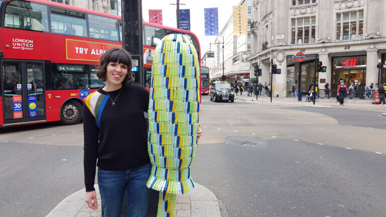 Ella Daish stands next to the giant tampon applicator she created with period waste found on beaches