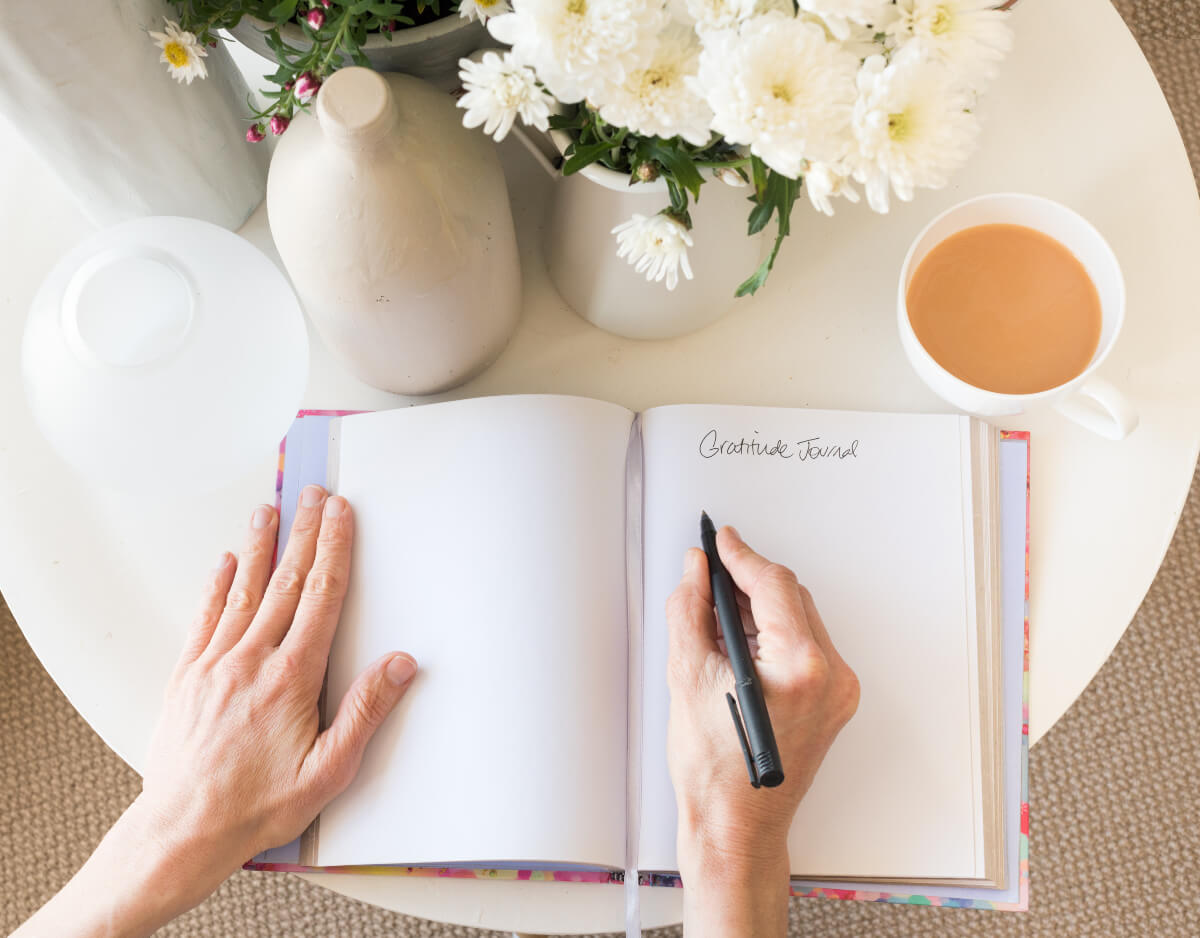 Open journal with the words "Gratitude Journal" written at the top of a page. Journaling can do wonders for one's mental health. 