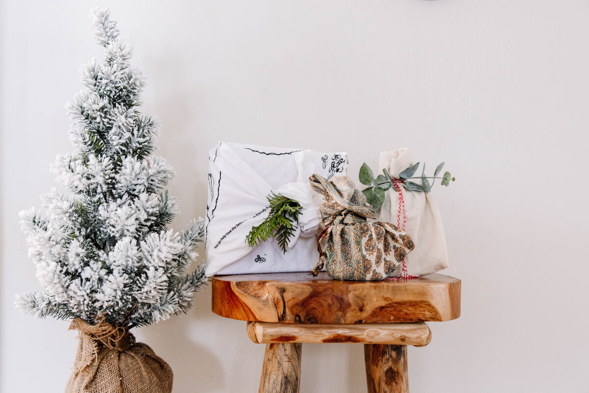 Reduce holiday waste by wrapping gifts in eco-friendly materials you have around the house, like these gifts wrapped in fabric and decorated with leaves. 