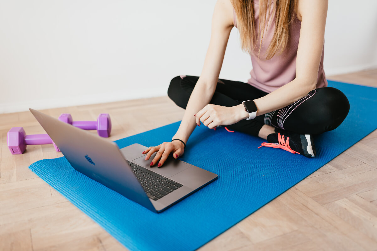 Person sitting on a yoga mat wearing a smartwatch and fitness attire 