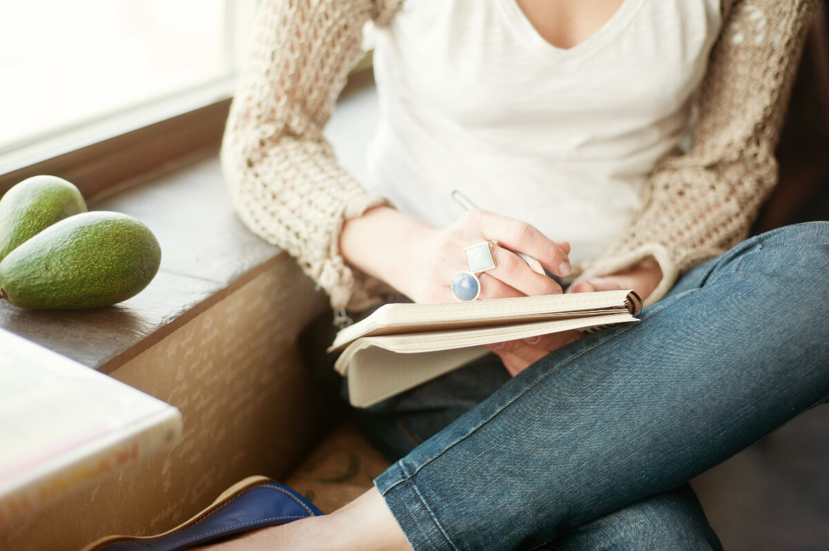Person curled up with a book and pen, ready to set their New Year's resolutions 