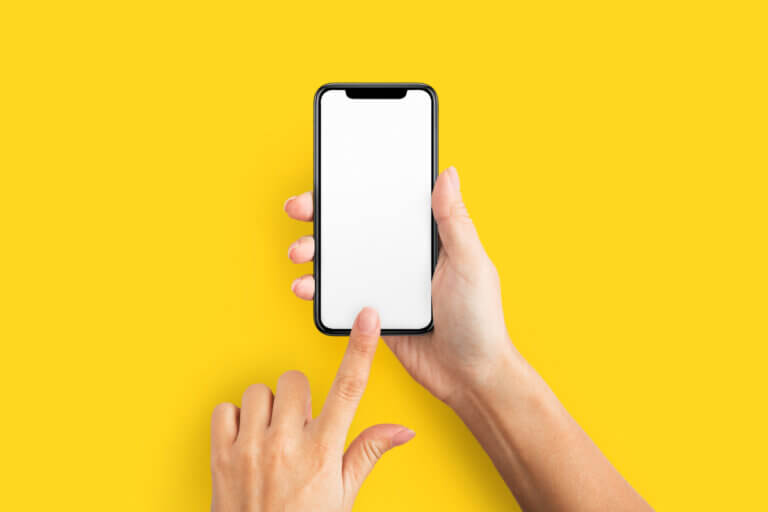 Person holding a smartphone in front of a yellow background