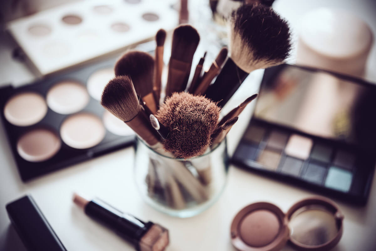Professional makeup brushes and tools, natural make-up products set on white table.