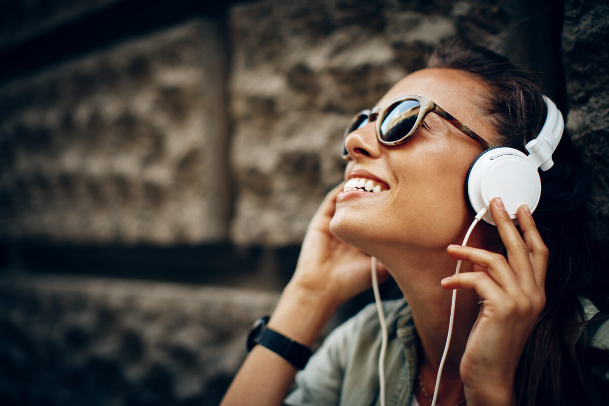 Woman wearing sunglasses and white headphones. 