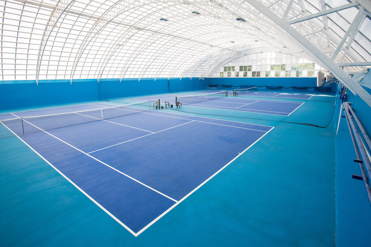 Background shot of modern indoor tennis court interior in blue colors, copy space