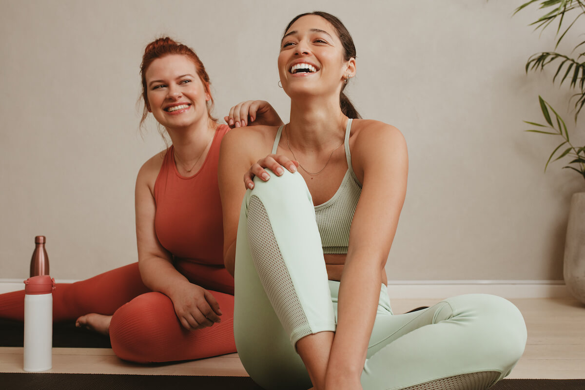 Cheerful women relaxing during a workout session. Smiling fitness women after exercising session in gym.