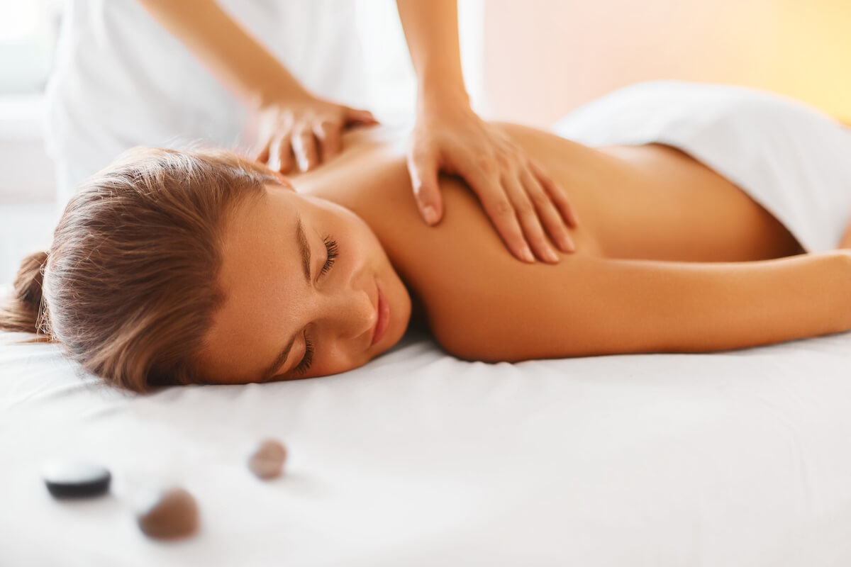 Female enjoying relaxing back massage in cosmetology spa centre. 