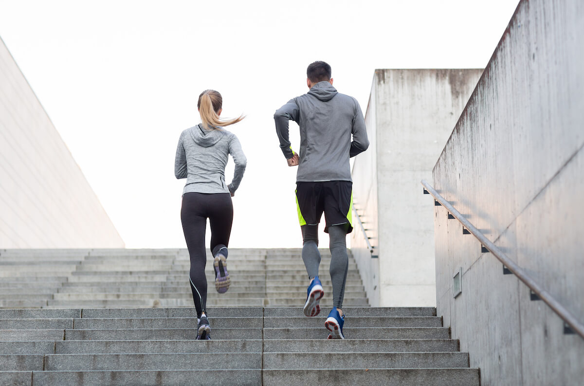 fitness, sport, people, exercising and lifestyle concept - couple running upstairs on city stairs