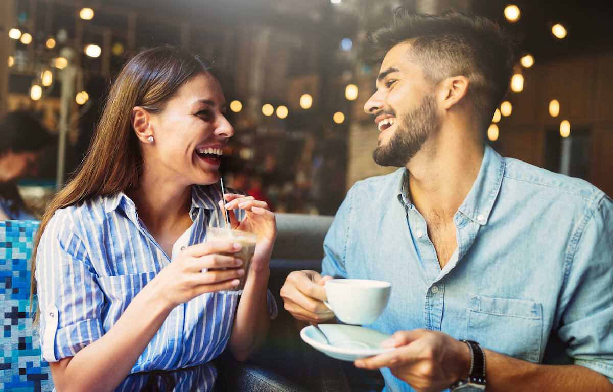 Young attractive cheerful couple on date in coffee shop