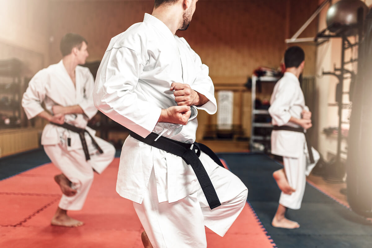 Martial arts karate fighters in white kimono and black belts on workout in gym