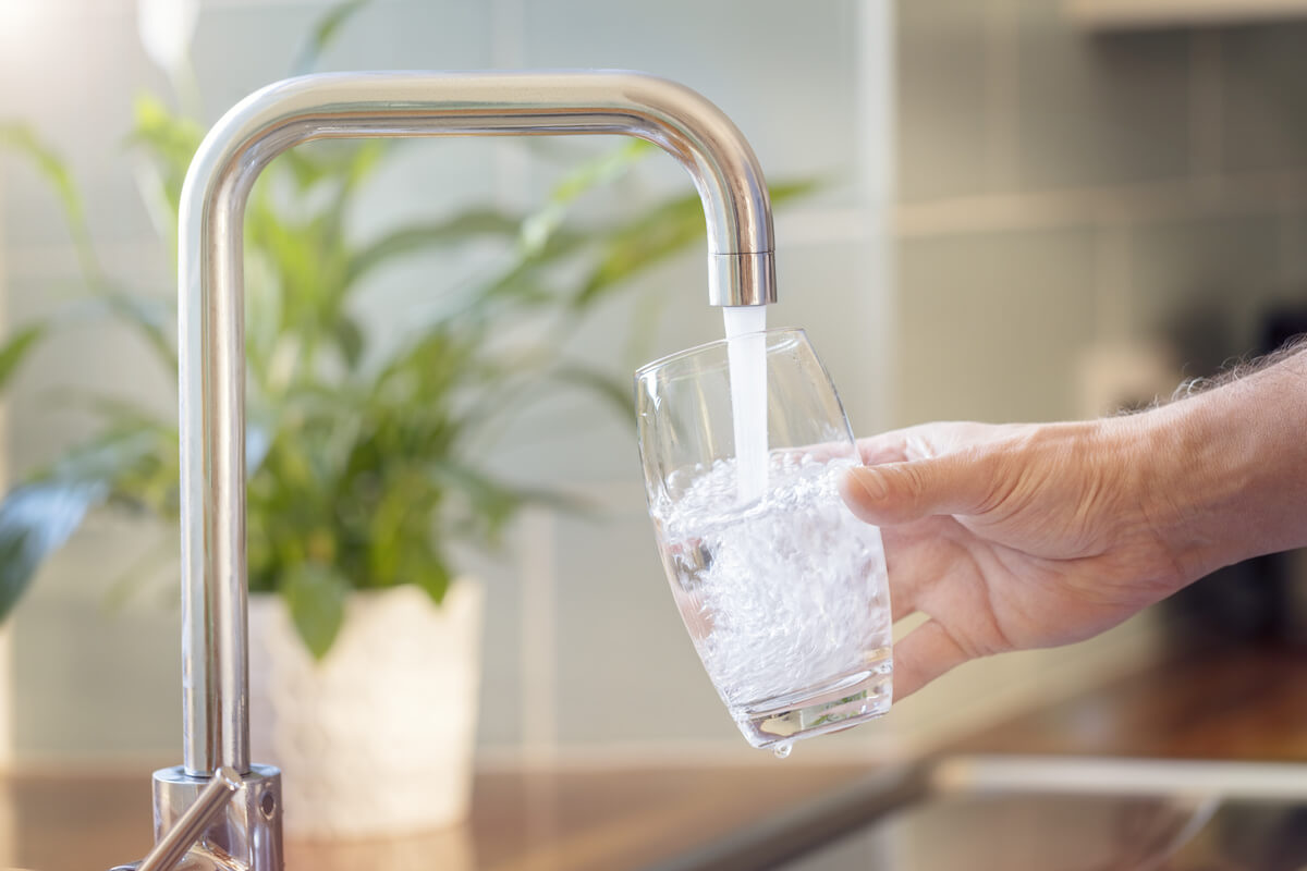 Filling up a glass with clean drinking water from kitchen faucet