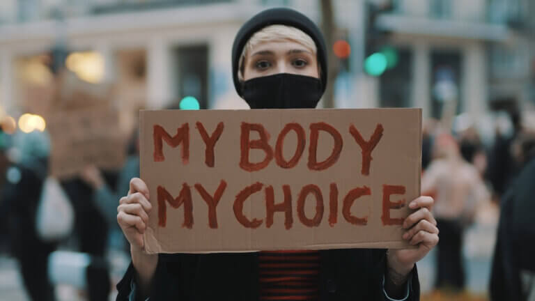 Woman holding a sign My Body, My Choice. Protest against tightening of the abortion law . Nationwide women's strike. Wearing protective face mask against COVID-19 Coronavirus.