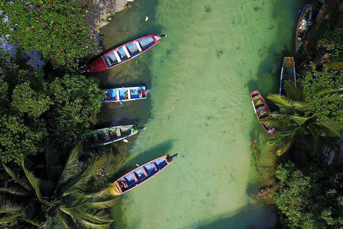 Aerial shot of White River, Ochos Rios, Jamaica with 4 colorful fishing boat moored in a small fishing settlement. Fishes are visible through the clear waters.
