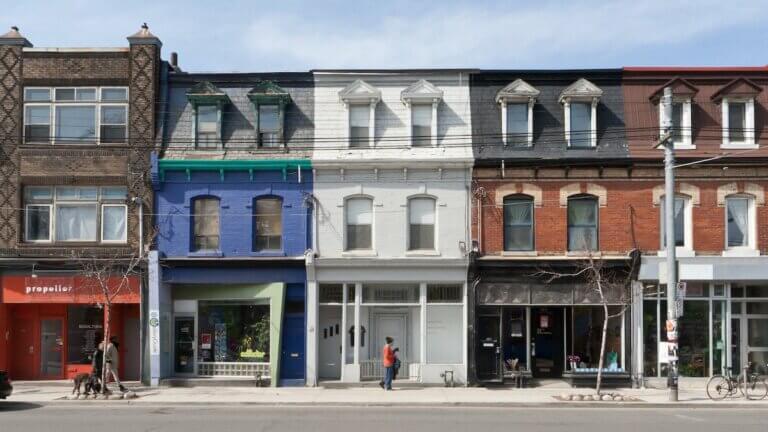 3 attached narrow buildings of different colours in Toronto