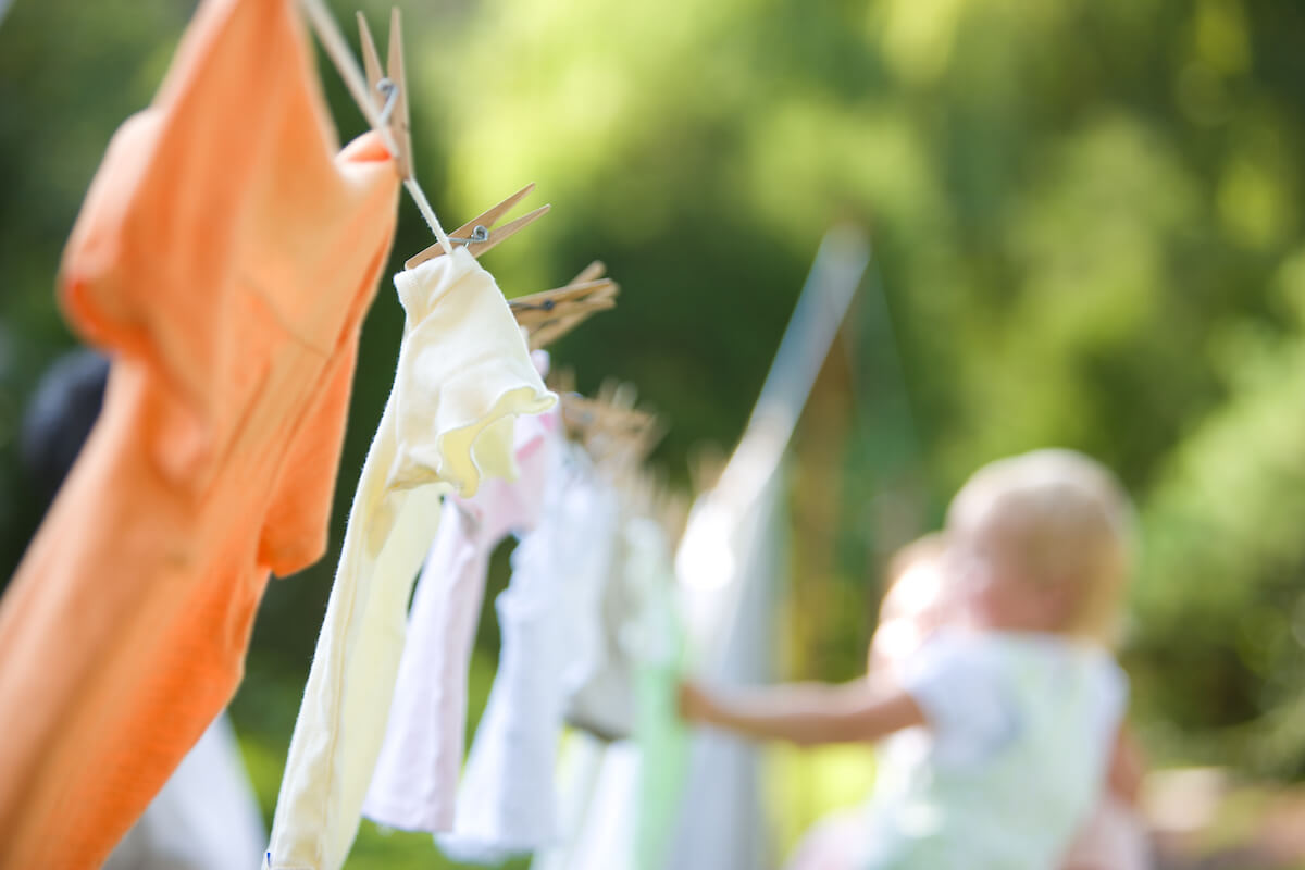 Clothes drying on a clothes line outside with a baby touching the clothes in the back ground