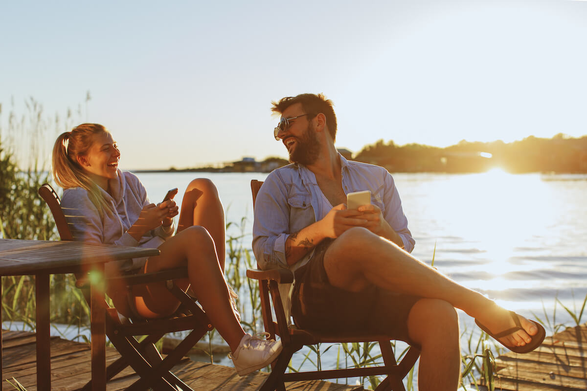 Young woman and man using smartphone by the river